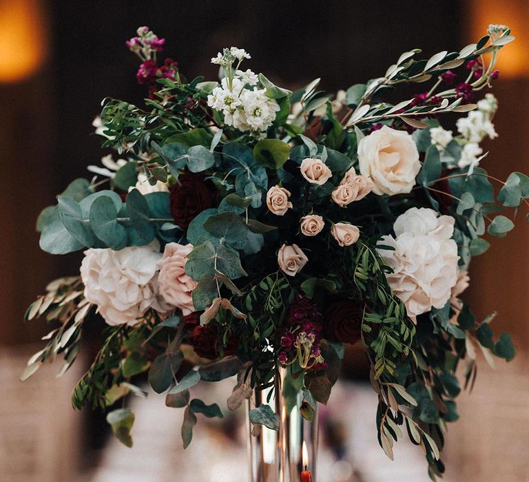 Red and burgundy taper candles decorate the wedding tables with tall centrepieces of red, pink, and white flowers 