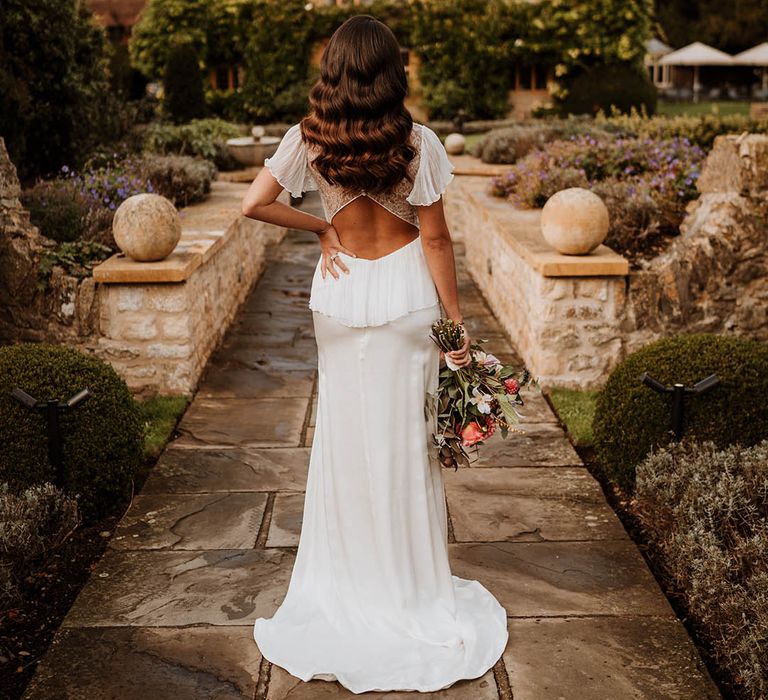 Bride in open back wedding dress with button details and butterfly sleeves posing at Oxfordshire wedding venue