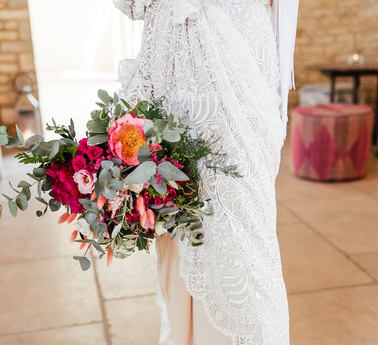 Bride in olive green chunky closed toe platform heels and long sleeve lace boho wedding dress holding bridal bouquet with red, pink and white garden roses, eucalyptus, foliage and dried flowers 