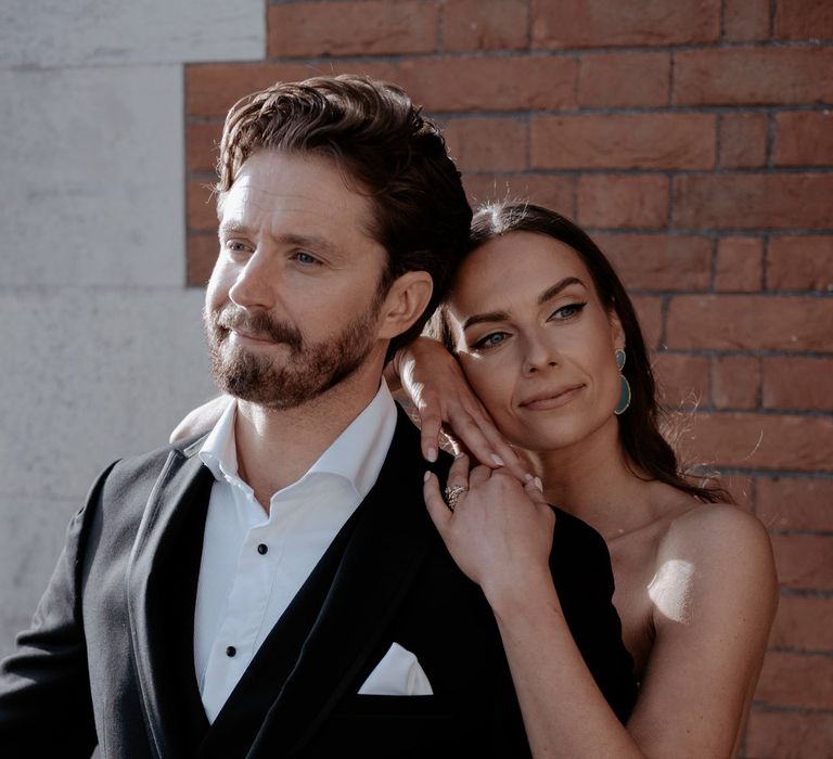 Groom in classic black blazer and suit trousers with white shirt and white pocket square and bride in strapless satin wedding dress 