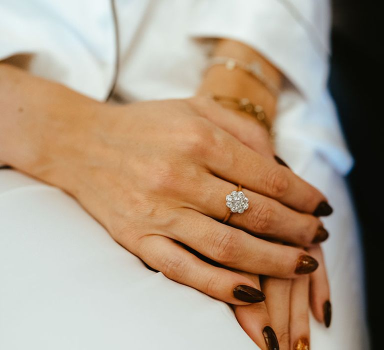 Bride wears floral styled diamond ring and dark nail polish 