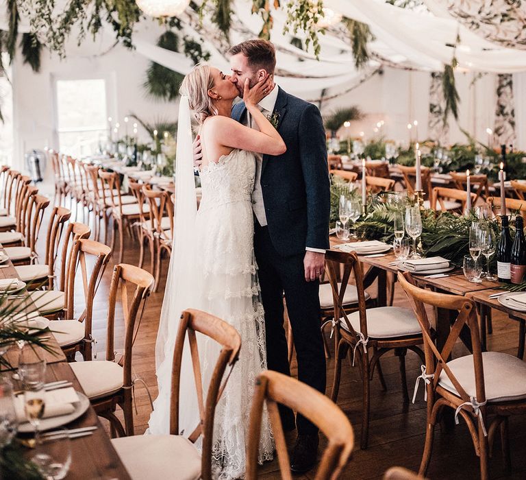 The bride and groom share a kiss as they stand in the marquee at Iscoyd Park for the greenery theme wedding 