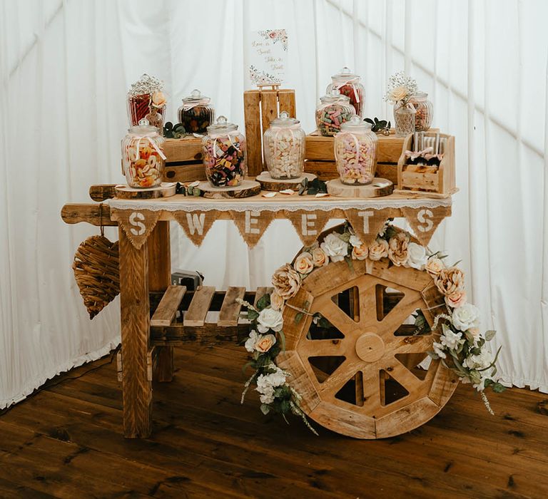 Sweet station wooden cart with big glass jars of sweeties for the guests to eat 