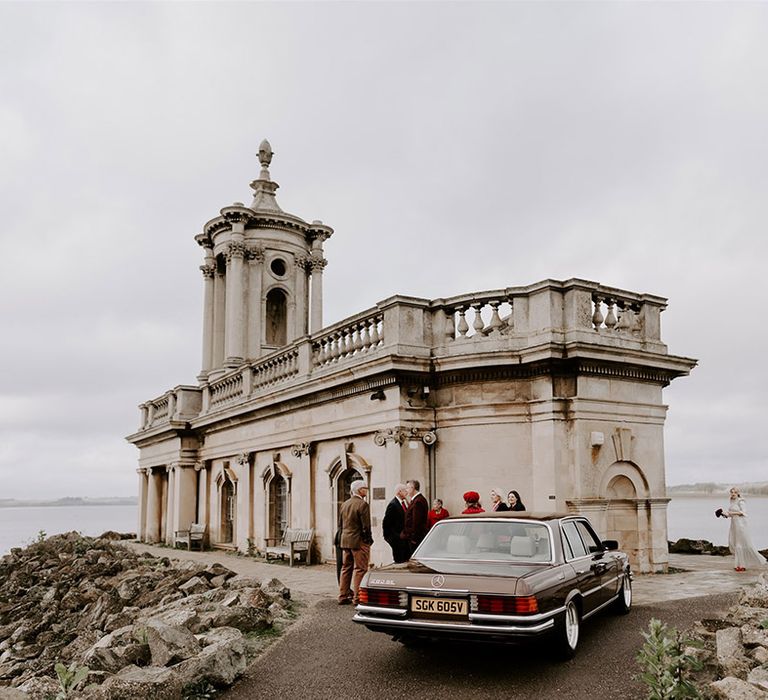 Gothic Normanton Church with the bride and groom exiting from the dark brown Mercedes wedding car with their wedding guests gathering 