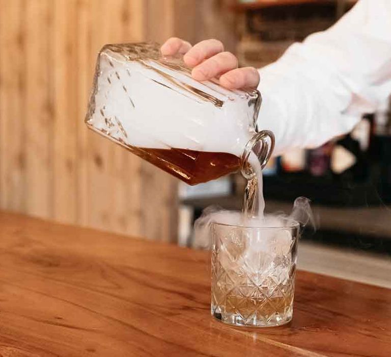 Bartender pouring fun wedding drink into a glass with smoke emerging at Lodge Farm 