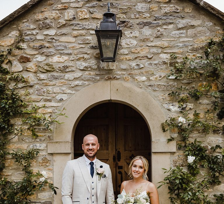 Bride in applique wedding dress by Alexandra Grecco with the groom in a light grey suit jacket and waistcoat 