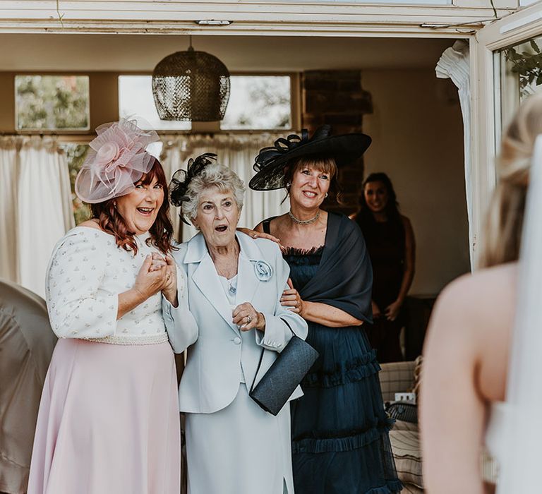 Female family members in their incredible wedding guest outfits get their first look at the bride in a Suzanne Neville wedding dress 