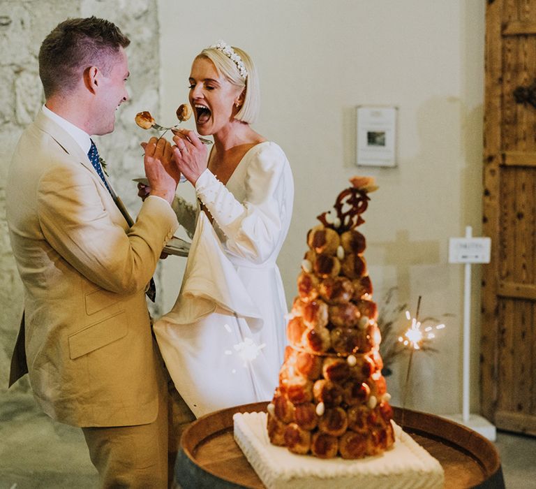 Bride and groom cutting their croquembouche wedding cake at French destination wedding