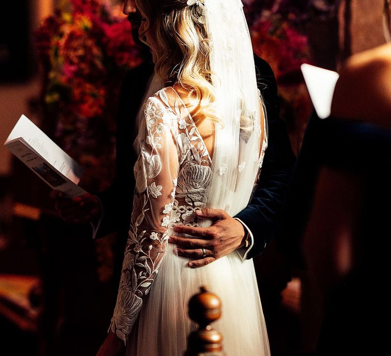 Groom embraces the bride as they stand for their church ceremony 