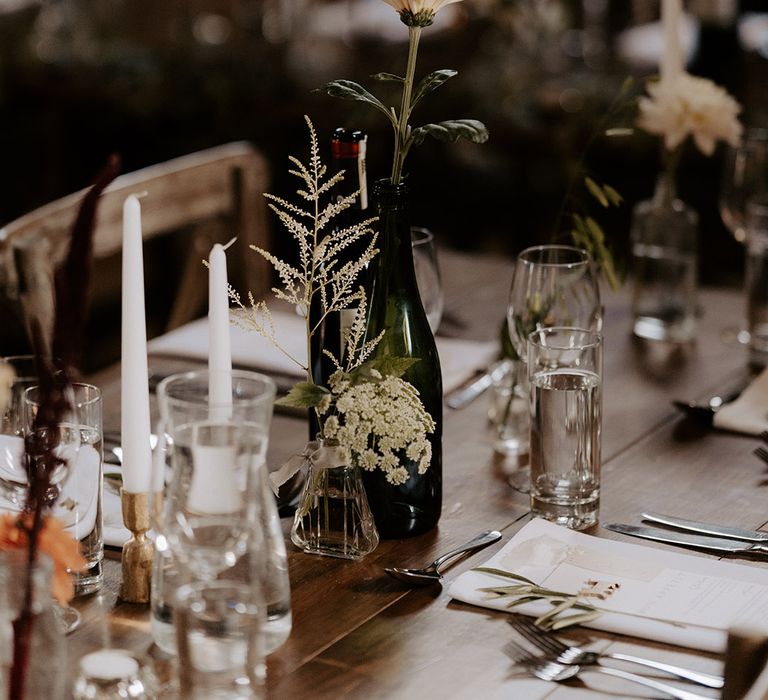 Old wine bottle filled with neutral wedding flowers for simple table decoration at rustic Bake Barn 