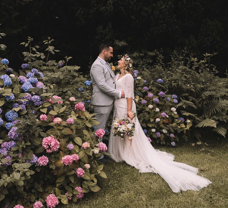 The bride and groom pose together outside their Wedding given for cute couple portraits at boho botanical wedding 