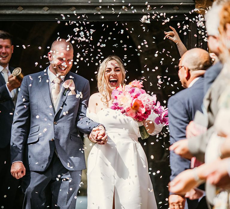 The bride and groom exit their church ceremony to white confetti 