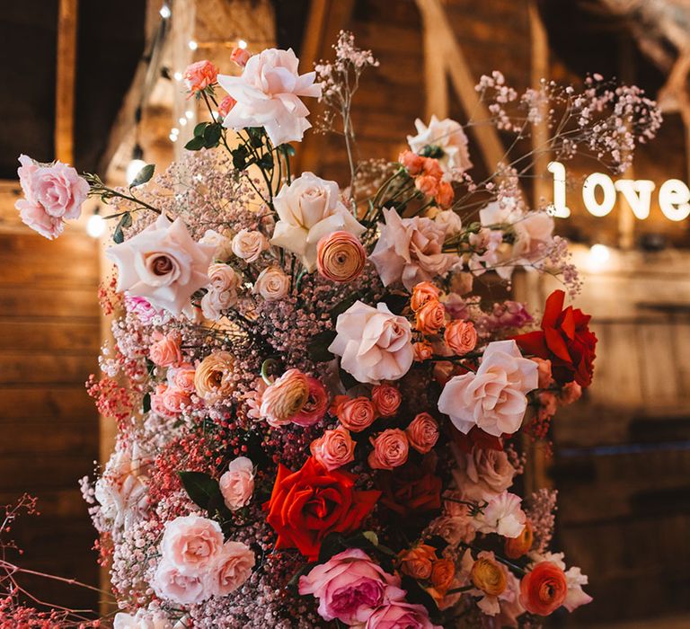 Light pink and red wedding flower column with gypsophila and red roses with neon sign 