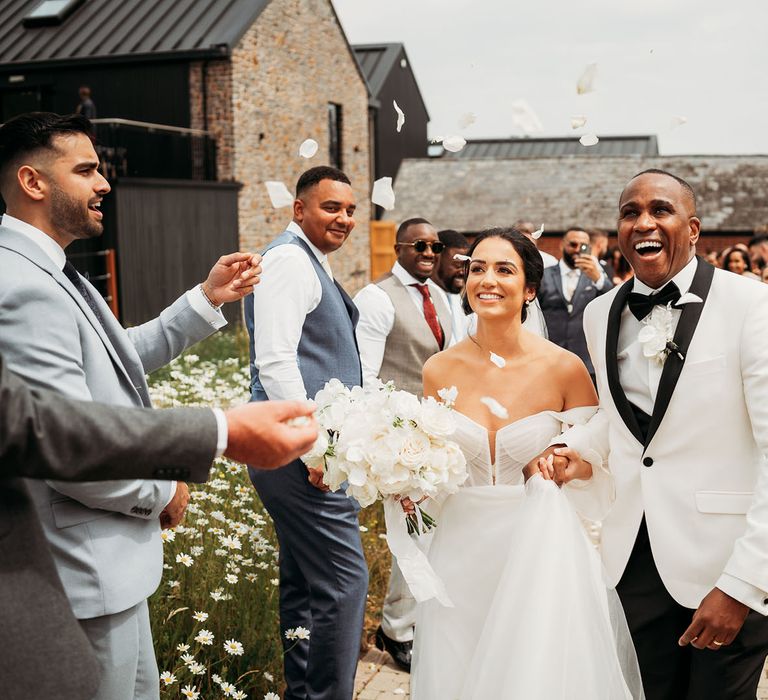 Bride and groom at confetti exit with white petal confetti at monochrome Crumplebury wedding