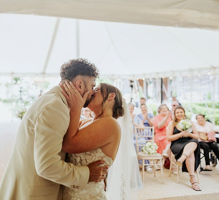 The bride and groom share their first kiss as a married couple at their monochrome wedding 