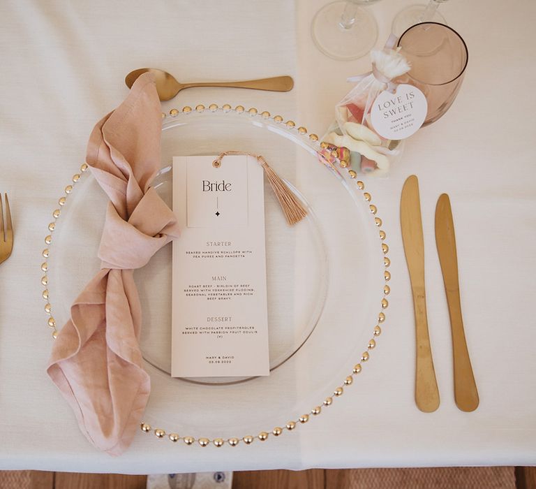 Pink and gold theme wedding place setting with wedding sweet favours and gold charger plate 