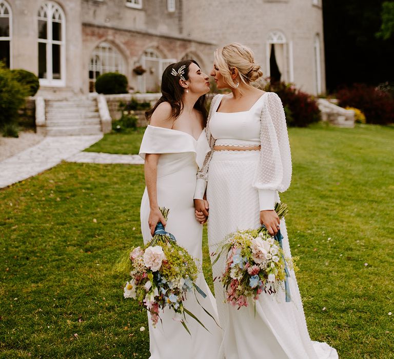 Two brides kiss in front of Pennsylvania Castle Estate wedding venue in the South West 