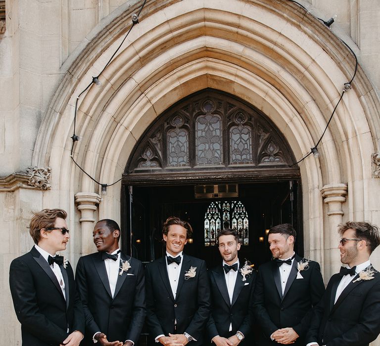 Groom and groomsmen in black tuxedos with boho dried flower buttonholes for boho luxe wedding