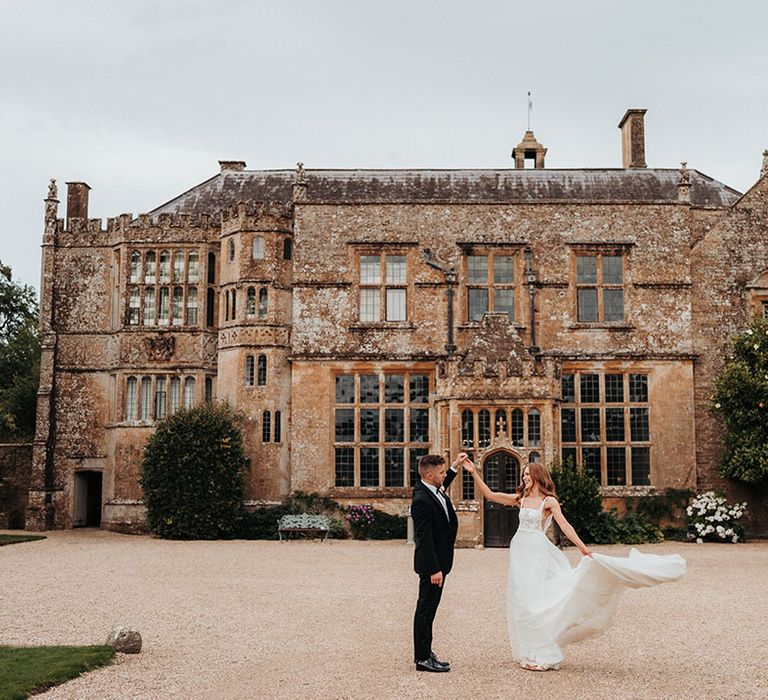 Brympton House wedding venue in Somerset with the bride and groom staying in front of the venue 