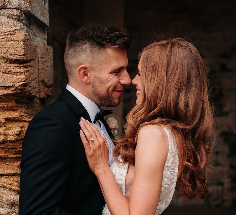 Groom in black tuxedo embraces the bride for cute wedding couple photo 