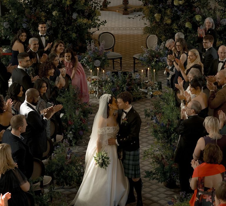 Married couple share a kiss walking back down the aisle at interfaith wedding 