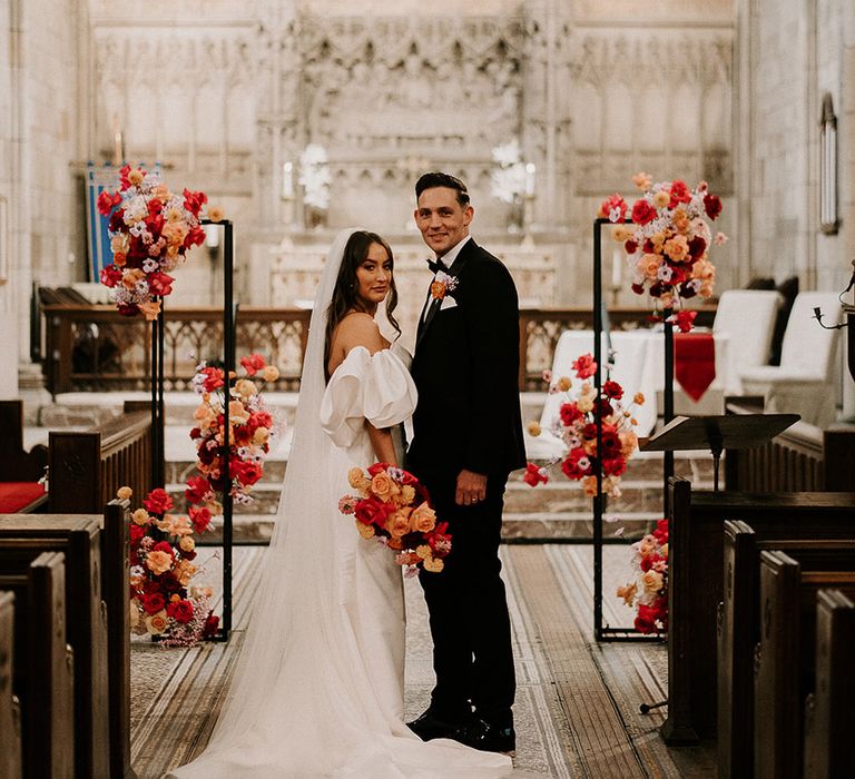 Colourful wedding flowers with pink, red and orange roses decorating the altar 