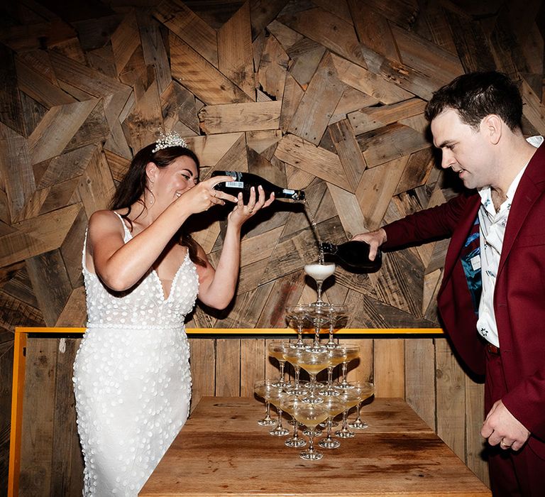 The bride and groom pour champagne into their champagne tower 