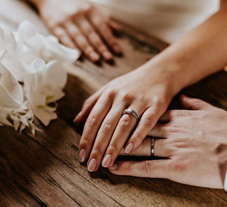 Bride with classic French tip wedding nails wearing a platinum and diamond wedding ring stack with round diamond engagement ring