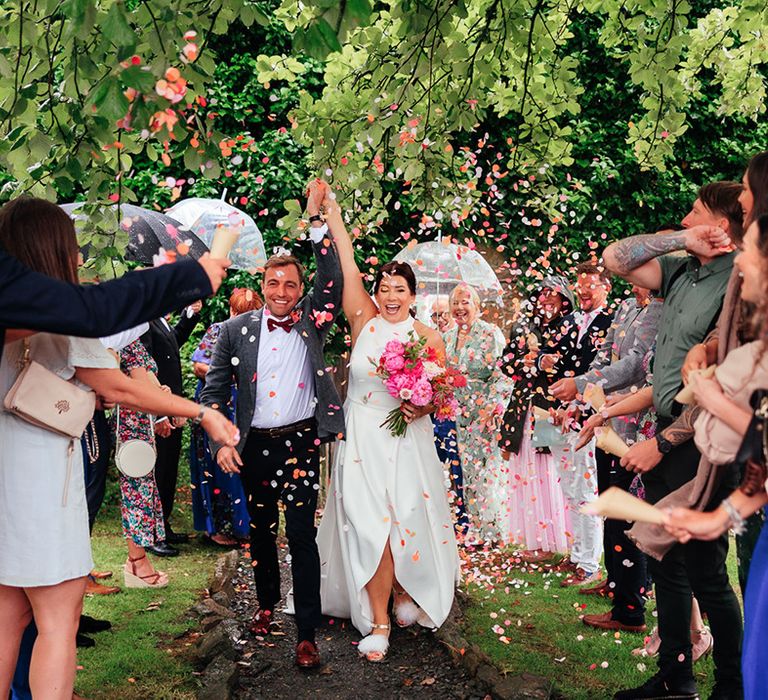 Colourful pink and white confetti moment for the bride and groom as they exit from their ceremony