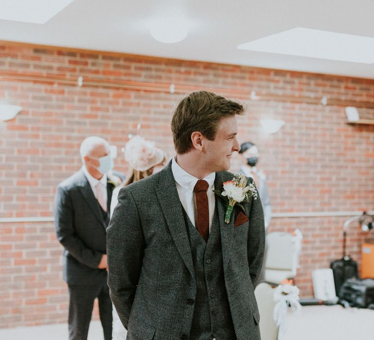 Groom in grey check suit at the altar 