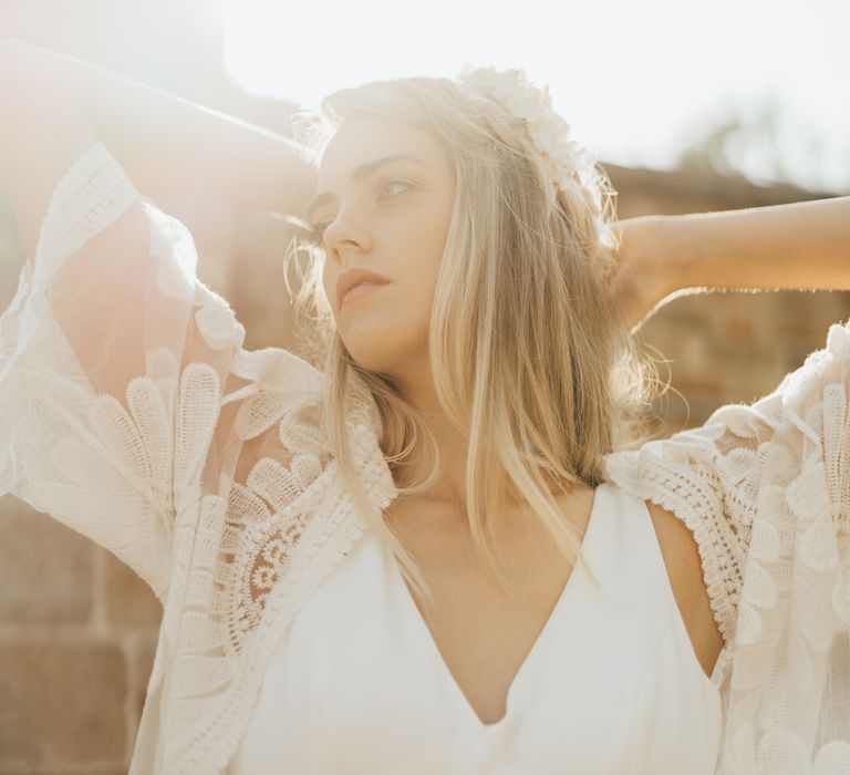 Bride poses in golden hour with lace cardigan and satin wedding dress