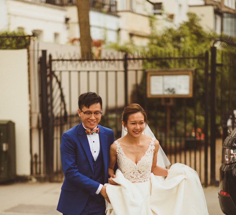 Groom helping his bride with her dress when crossing the street 