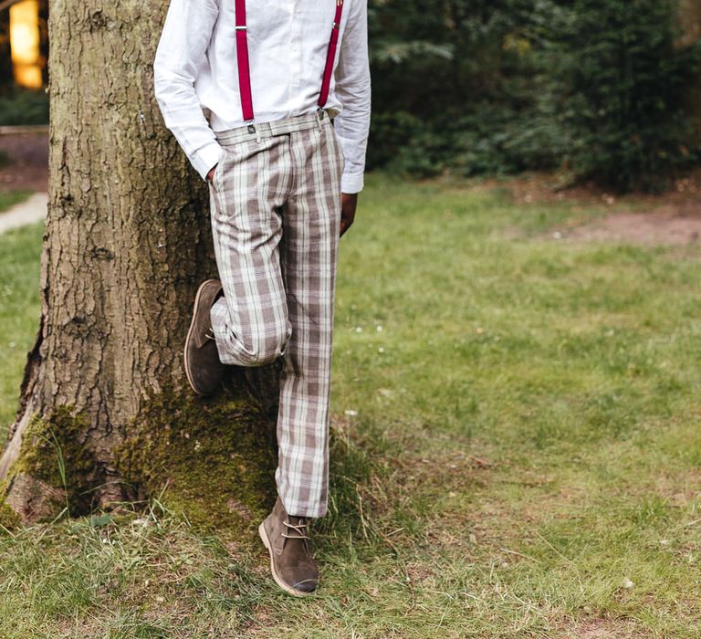 Groom poses in braces and tartan trousers 