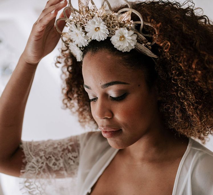 A Black bride wears loose curly hair with large bridal crown. Wedding hairstyles for Black brides.