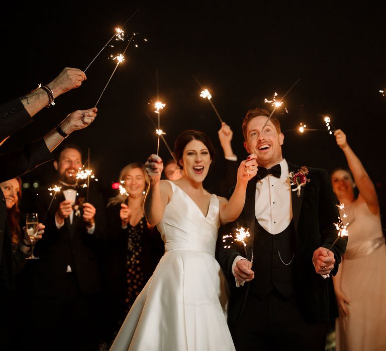 Bride and groom celebrating with their guests with sparklers