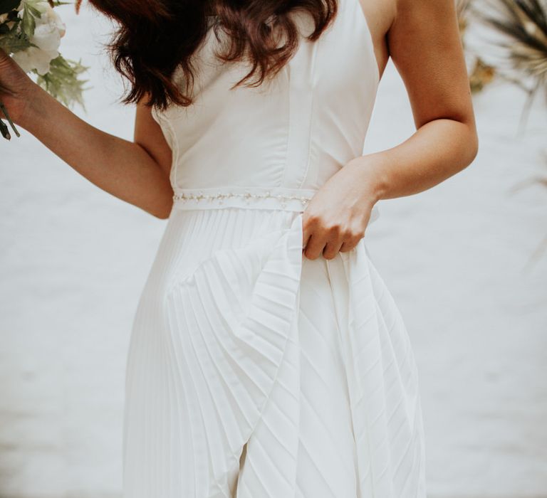 The bride wore a pleated wedding skirt to match the dried palm leaf decor