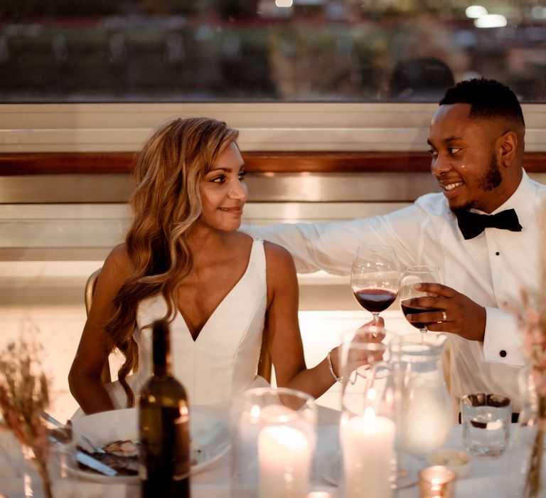 Bride and groom cheers at their intimate candlelit wedding reception 