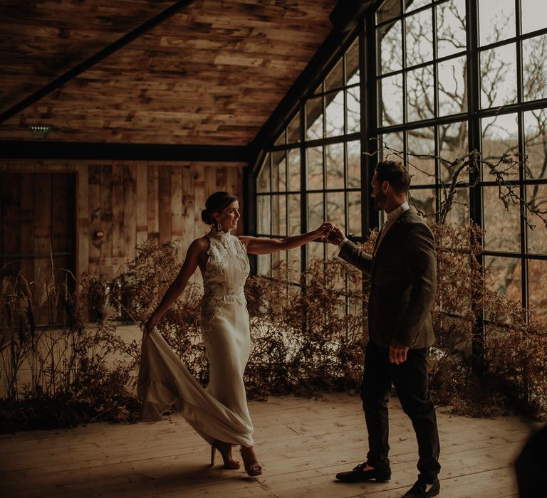 Dried flower floral arrangements and bride in a halter neck wedding dress dancing with her groom at Hidden River Cabins wedding venue 