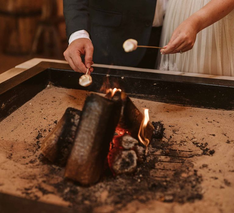 Brie & groom toast marshmallows in wedding tipi