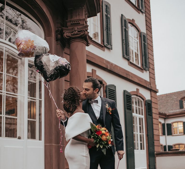 Bride & groom stand together outdoors as bride holds Autumnal bouquet