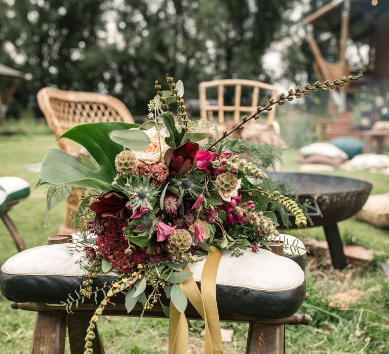 Floral bouquet featuring red blooms and green foliage on wooden chair