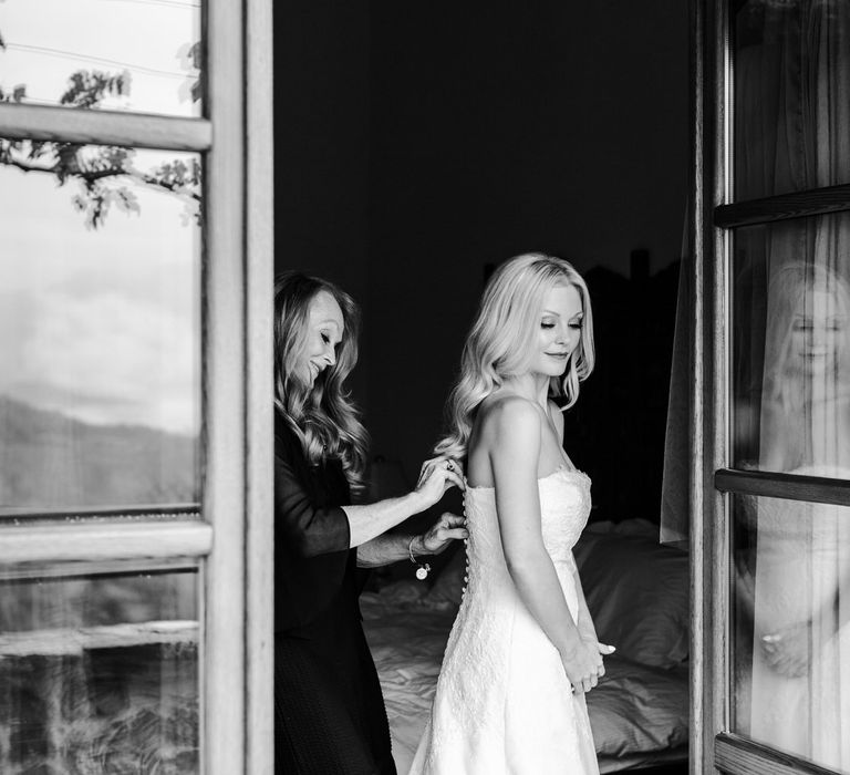 The bride having her wedding dress fastened