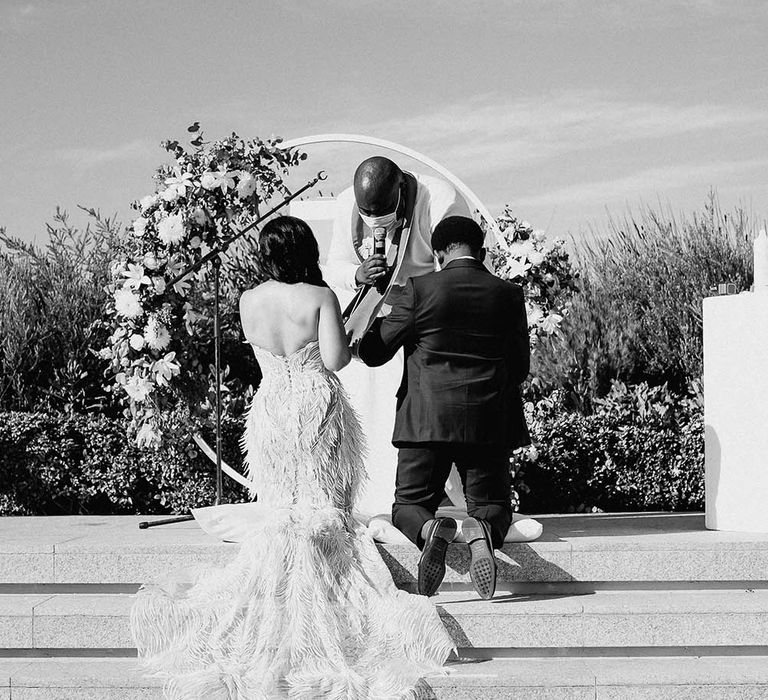 Bride and groom kneeling down during their religious wedding ceremony 