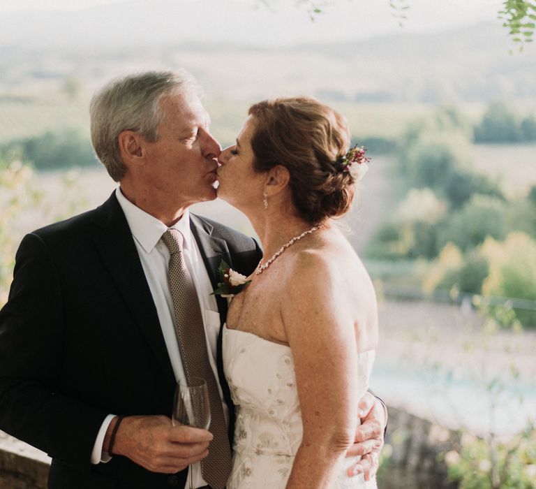 Bride & groom kiss in the sunshine whilst the Italian countryside can be seen in the background