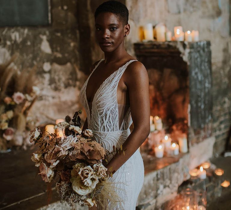 Beautiful black bride with short hair in an embellished Made With Love Bridal gown holding a neutral dried and fresh flower bouquet 