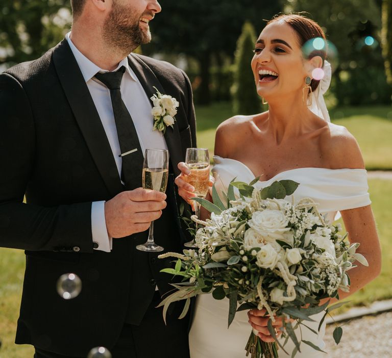 Bride and groom toast as the bride clutches large wedding bouquet