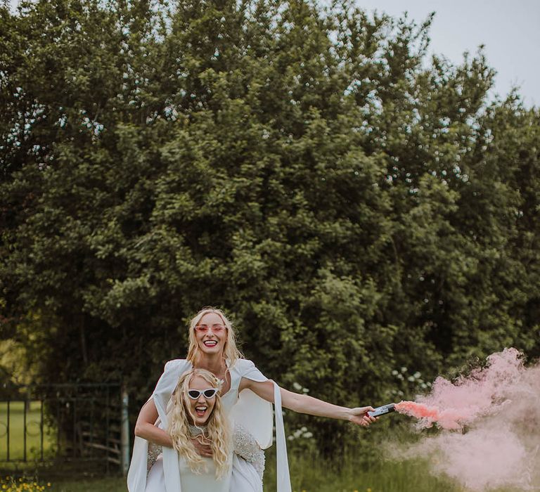 LGBTQI+ couple portrait in a field with a pink smoke bomb 