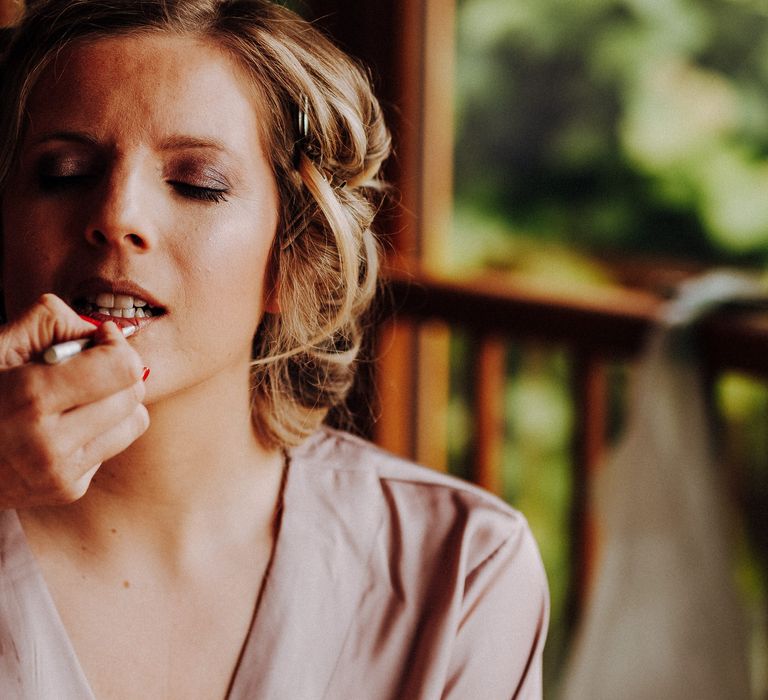 Bride has her makeup done on the morning of her wedding as she wears lavender dressing gown