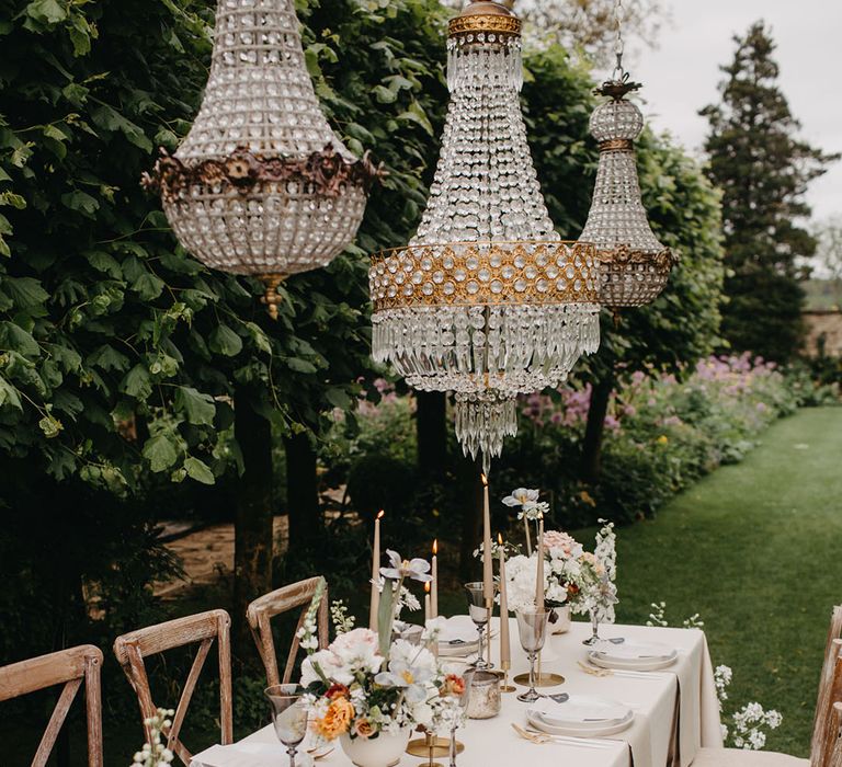 Elegant wedding table decor with Chandelier installation and taper candles 