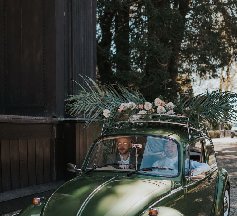 Two grooms in a green beetle wedding car 